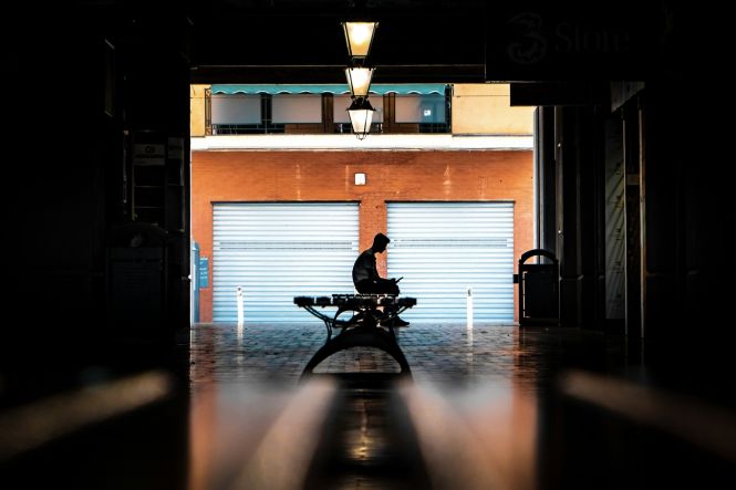 Silhouette of a person sitting on a bench. Photo by Chris Curry on Unsplash