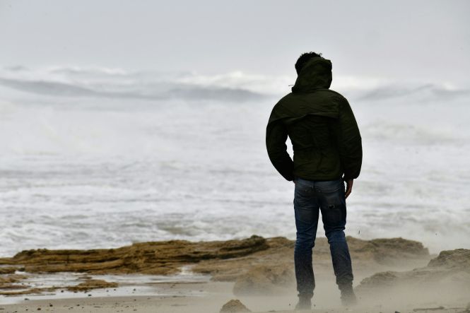 A person alone on the beach on a stormy day. Photo by shraga kopstein on Unsplash